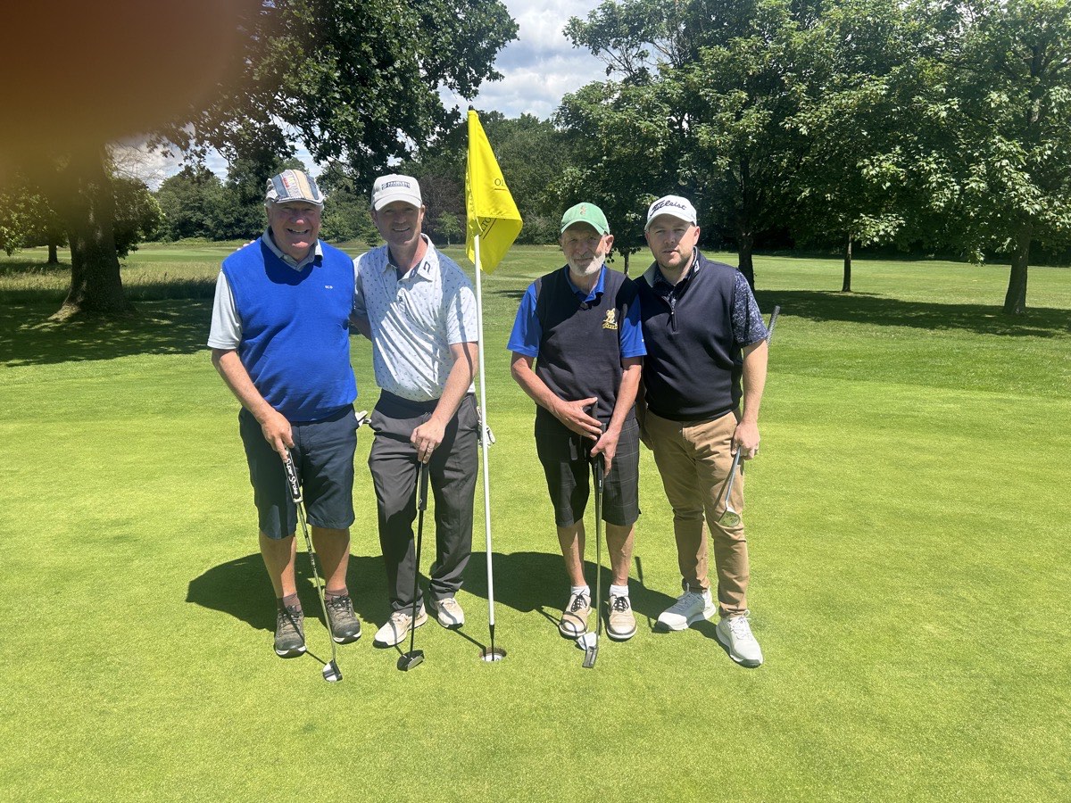 Four players beside the flag on a sunlit green at Olton
